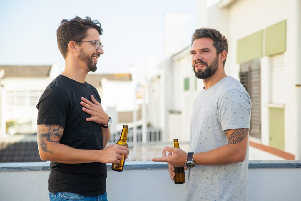 Two men talking outside with drinks