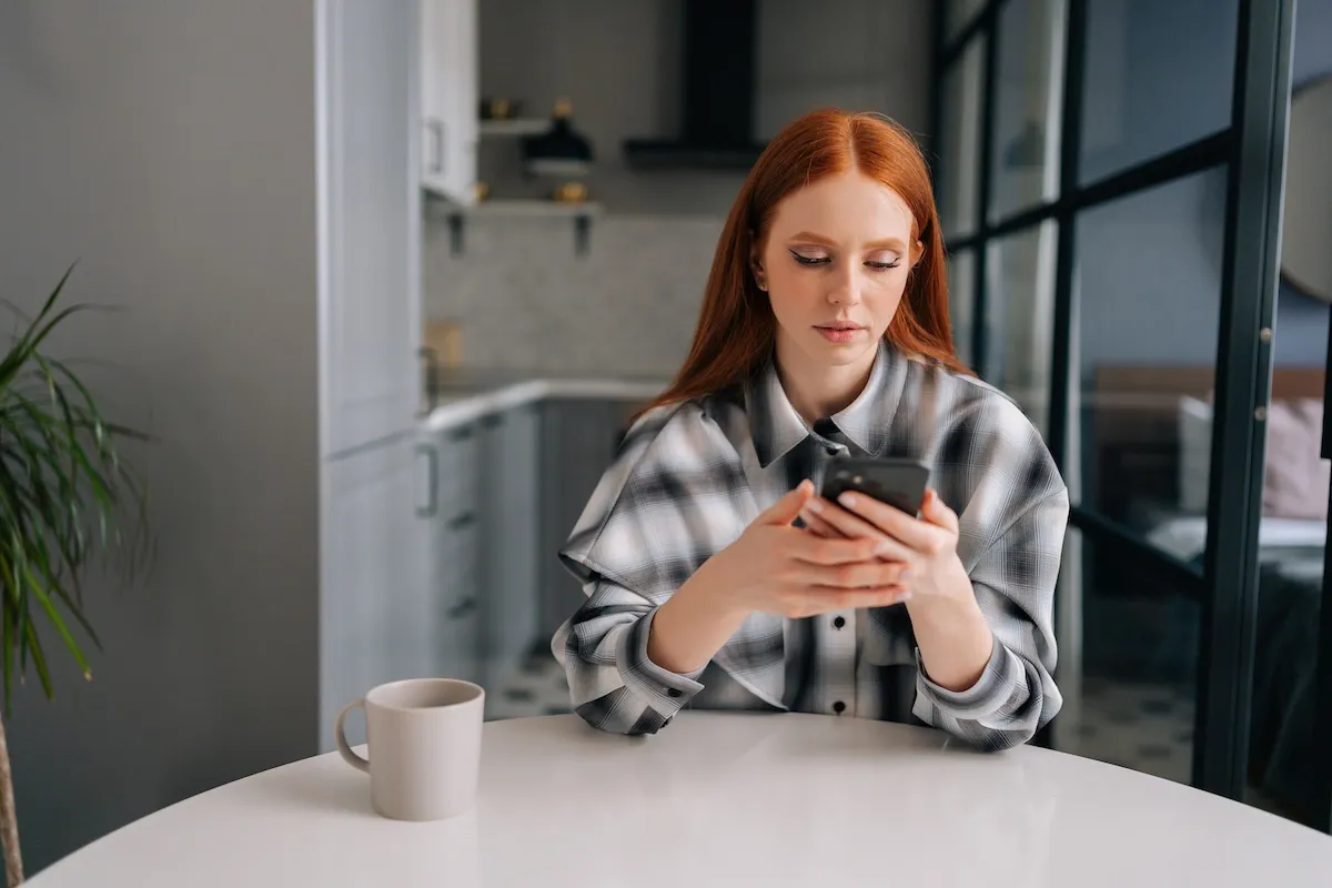 Woman sitting at a table texting someone with a serious look on her face